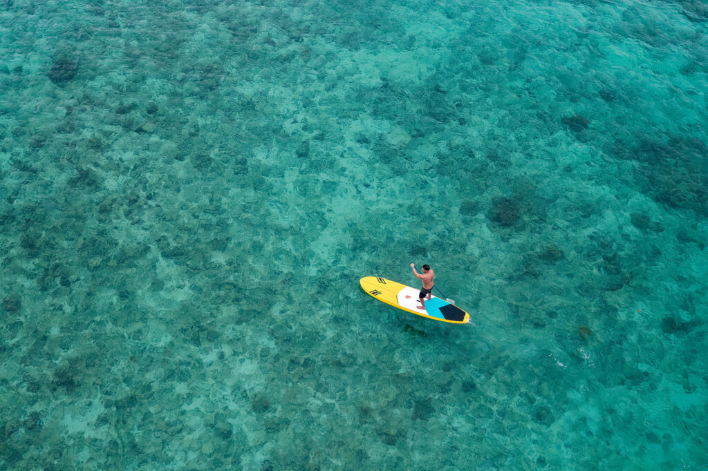 Drone image of a stand up paddle board rider in the blue waters of Fiji.